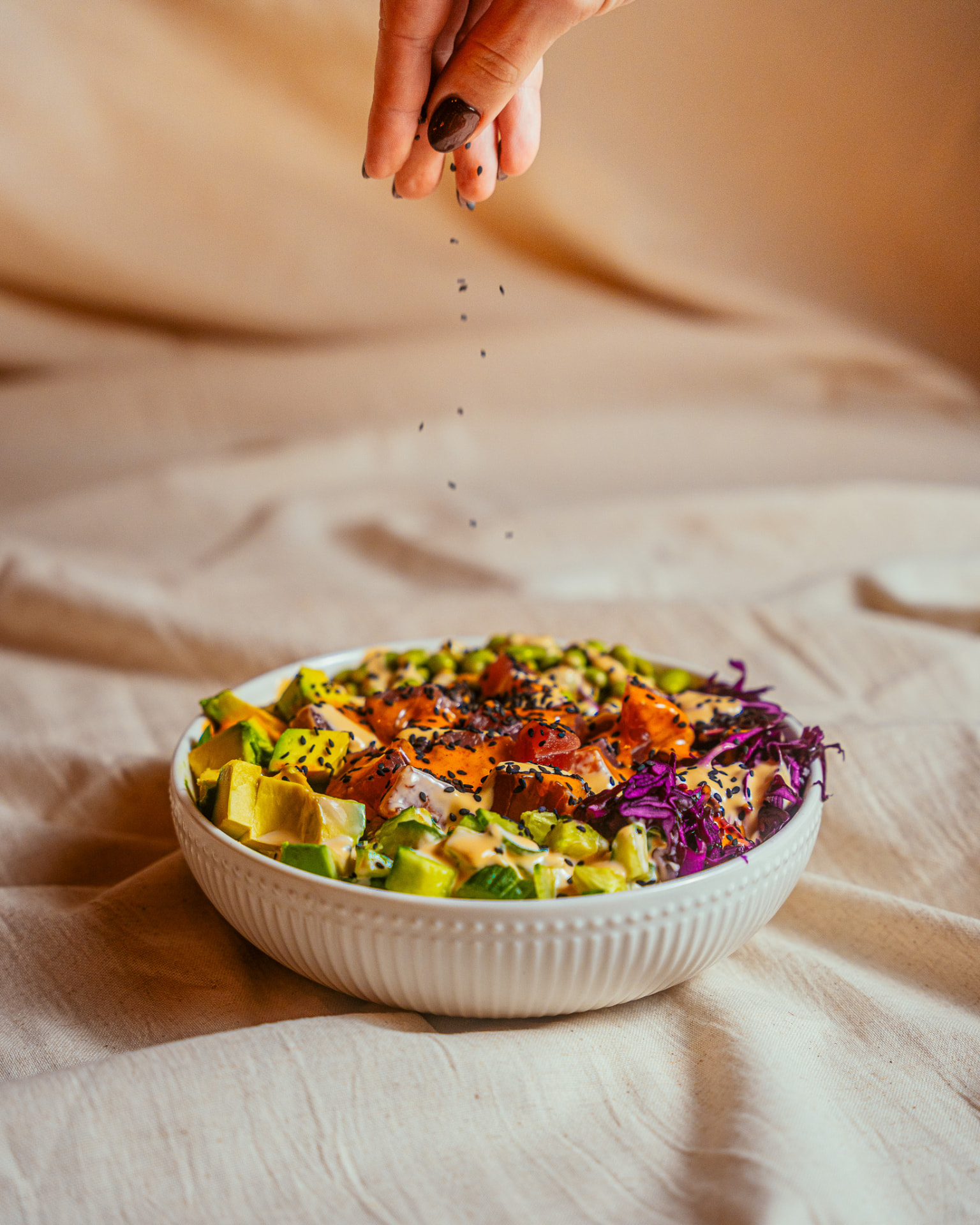 Bowl mit Avocado, Lachs und Rotkohl wird mit Sesam bestreut